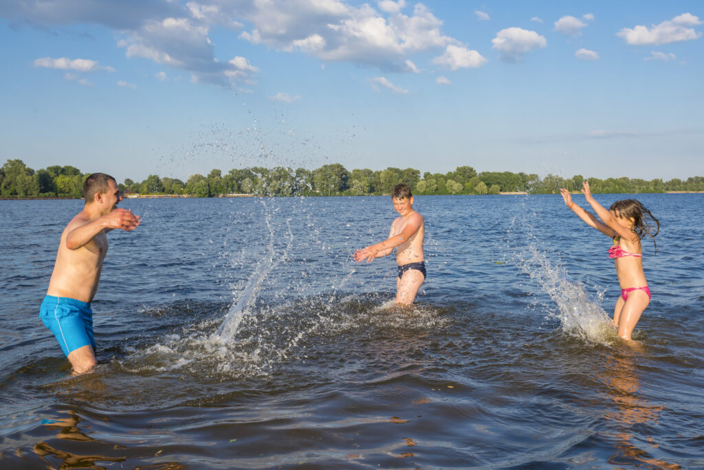 Happy family have fun playing in the river on summer vacation. Family outdoor sports games. Active healthy lifestyle concept